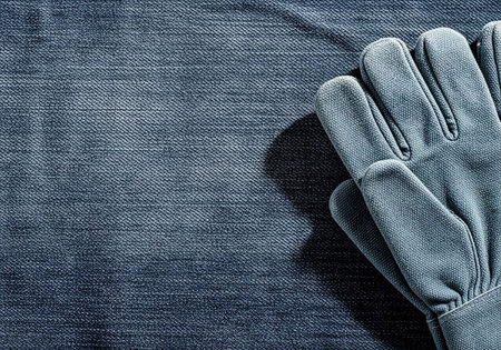 A close-up view of a gray glove on a denim fabric backgroundの写真素材