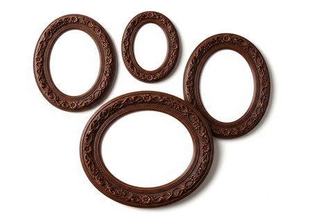 Four empty brown picture frames with intricate designs on a white backgroundの写真素材