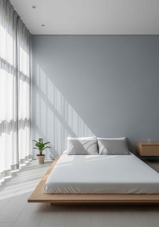 A serene bedroom with a wooden bed frame, white bedding, and a potted plant beside a large window with sheer curtains.の写真素材