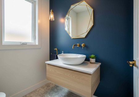 A modern bathroom with a white sink and gold fixtures on a blue wallの写真素材