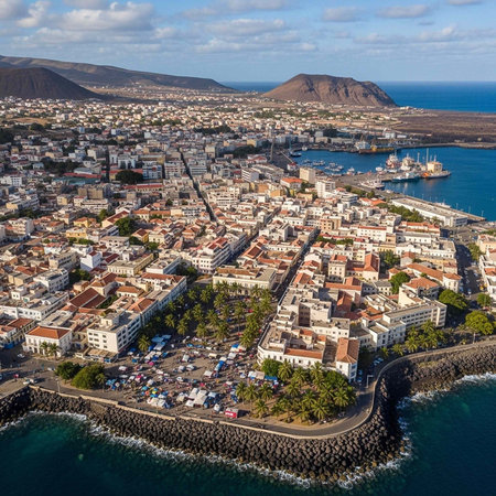 Aerial view of a coastal city with a harbor and mountainous landscape in the background