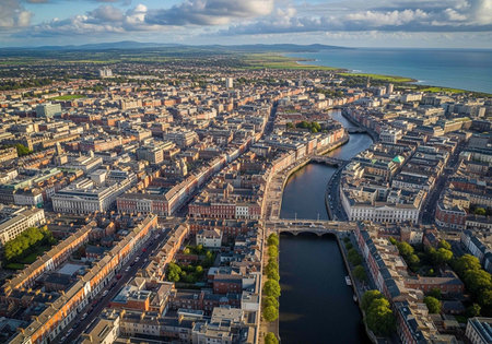 Aerial view of a vibrant city with a river and bridge under a cloudy skyの写真素材