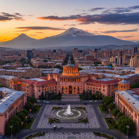 Aerial view of a city with a large building and fountain at sunset