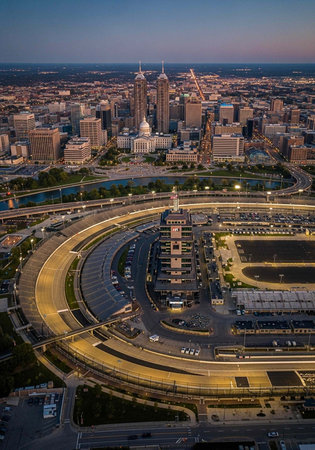 Aerial view of a cityscape with a large racetrack and urban landscape at dusk