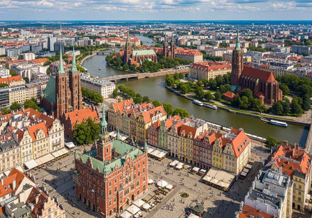 Aerial view of a city with a river, featuring historic buildings, red roofs, green spaces, and a...