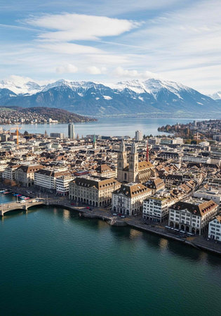 Scenic cityscape of Lucerne with lake, buildings, and snow-capped mountains under blue skyの写真素材