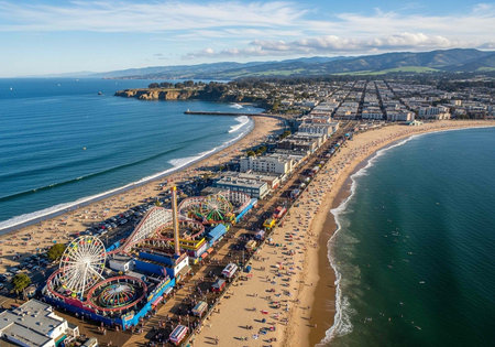 Aerial view of a bustling beachside amusement park with Ferris wheel, sandy beach, and cityscape