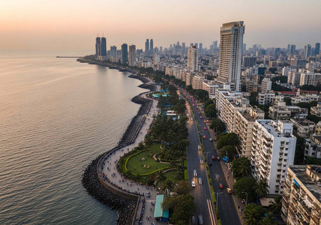 Aerial view of a coastal city with modern buildings, a road, and calm water at sunset.の写真素材