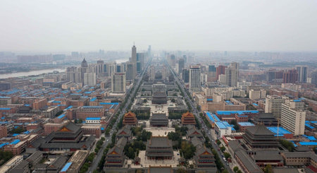 Cityscape with mix of traditional and modern buildings, roads, and trees under hazy sky