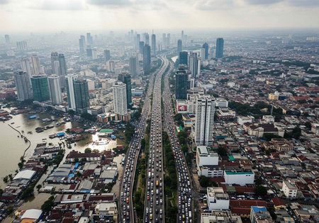 Aerial view of a congested city with a busy highway, skyscrapers, and buildings