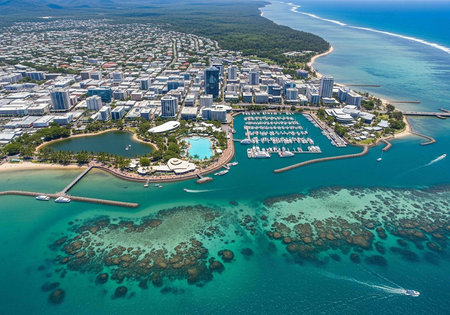 Aerial view of a coastal city with a marina, beaches, and coral reefs in turquoise water, featuring modern buildings, docks, and boats.の写真素材