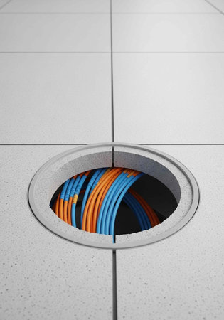 A round hole in a white tiled floor revealing colorful cables underneath