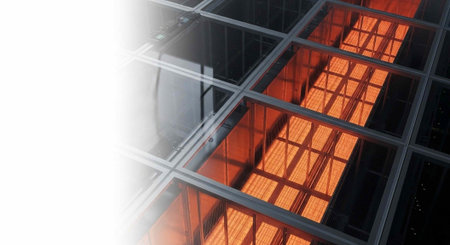 A modern glass building with orange light shining through its windows at night