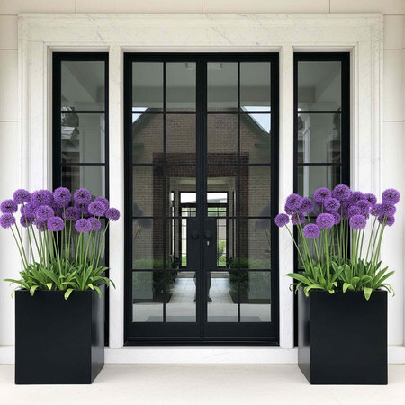 A modern building entrance with large glass doors and purple flowers in planters