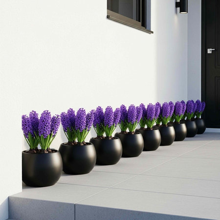 A row of black pots with purple flowers on a modern building's entranceの写真素材