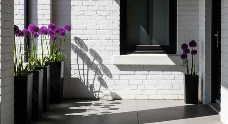 A modern white brick building with purple flowers in black planters on a sunny day