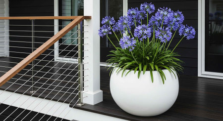 A large white planter with purple flowers sits on a modern porch with a metal railingの写真素材