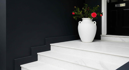 White marble staircase with vase of red flowers on top step against dark backgroundの写真素材