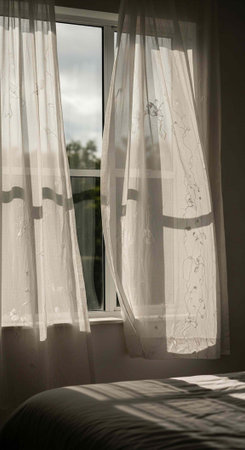 A serene bedroom interior with sheer curtains and a view of the outdoors