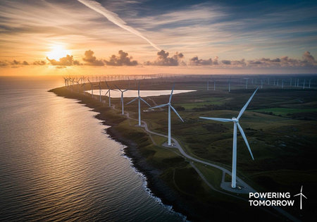Wind turbines on a small island surrounded by calm waters at sunset with a cloudy sky