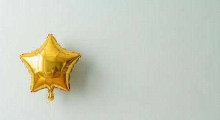 A shiny gold star-shaped balloon against a plain light gray background with empty space.の写真素材
