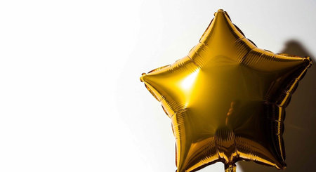 Close-up of shiny gold star balloon with shadow on whiteの写真素材