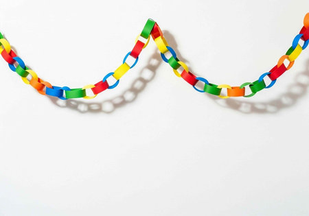 Rainbow-colored chain links casting shadows on plain white surfaceの写真素材