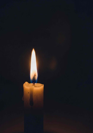 A single lit candle in a dark room with a warm glow
