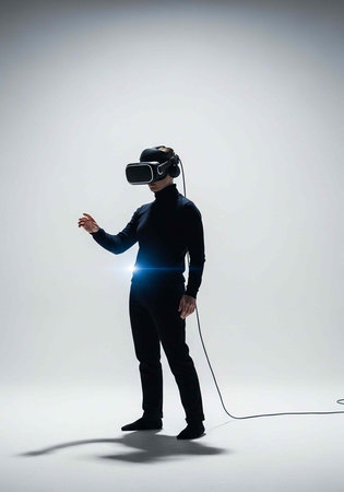 A man wearing a virtual reality headset and standing in a white room with a cord attached to his...