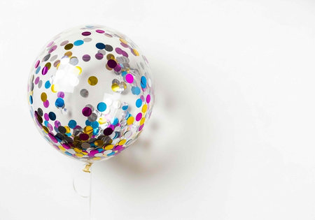 A shiny balloon with colorful confetti dots floats in the air on a white background
