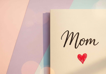 A pastel colored card with the word Mom and a red heart on it for Mother's Day