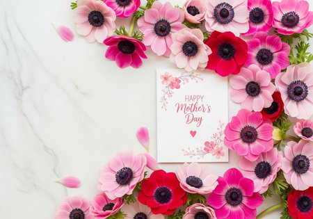 Colorful flowers surround a Happy Mother's Day card on a white marble surfaceの写真素材