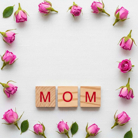 A beautiful arrangement of pink roses and wooden blocks with the word MOM on a white background
