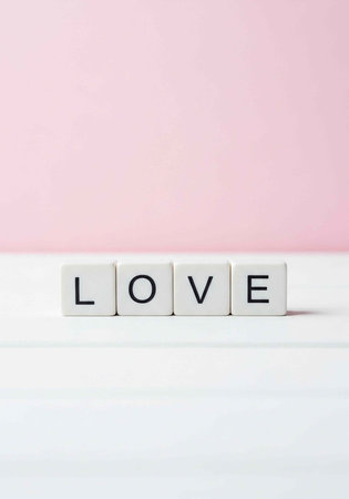 A minimalist composition featuring the word love spelled out in blocks on a pink and white...