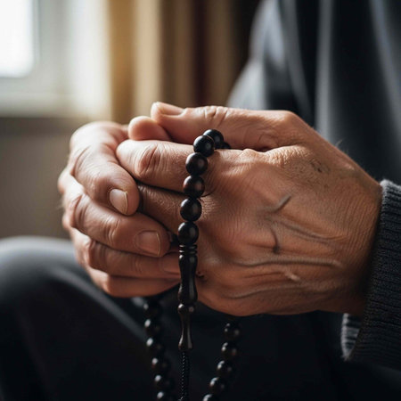 A person holds a black rosary in their hands in a moment of prayer or contemplation.