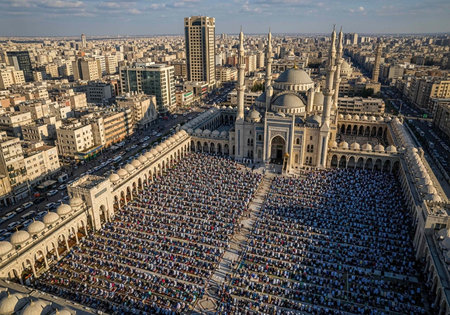 A large crowd of people gathered in front of a mosque in a city