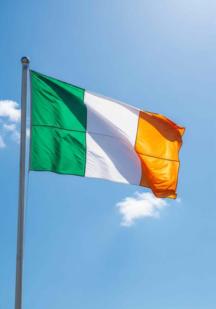 The Irish flag waving in the wind on a sunny day with a clear blue sky