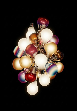 A cluster of light bulbs in various colors including red, gold, and white on a black background