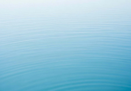 A serene and peaceful blue water background with gentle ripples and soft lightの写真素材