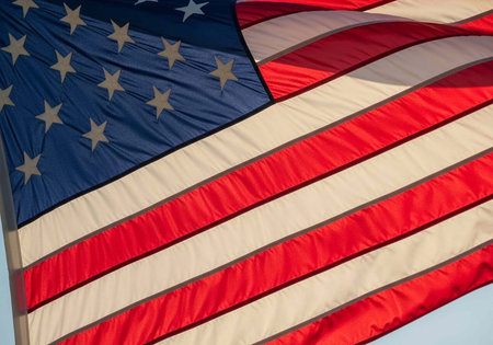 The American flag waving in the wind on a clear day with a blue sky