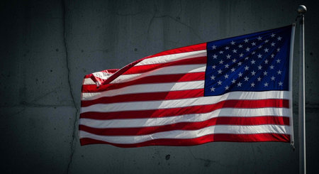 The American flag waving proudly on a flagpole against a dark concrete background