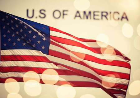 The American flag waving proudly with the U.S. of America text in the background