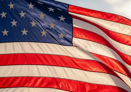 The American flag waving in the wind with a clear blue sky in the background.