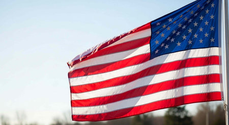 The American flag waving in the wind on a clear day with a blue sky