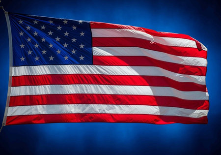 The American flag waving proudly in the blue sky with white stars and red and white stripes