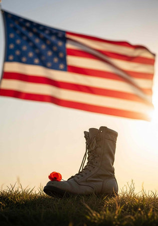 A US military boot and red poppy flower under the American flag at sunset symbolizing remembrance...