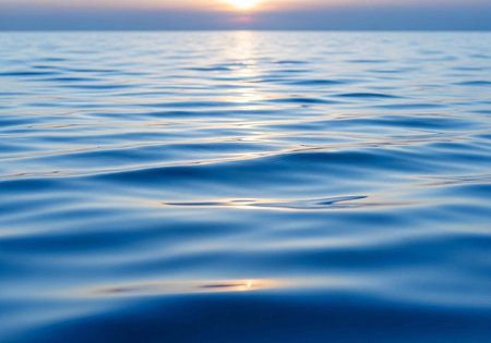 A serene ocean landscape at sunset with calm waters reflecting the vibrant colors of the sky