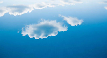 A serene blue sky with white clouds floating gently across the horizon on a peaceful day