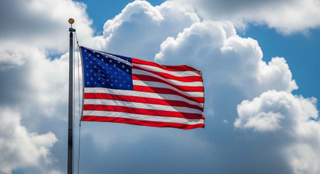 The American flag waving proudly in the sky with white clouds