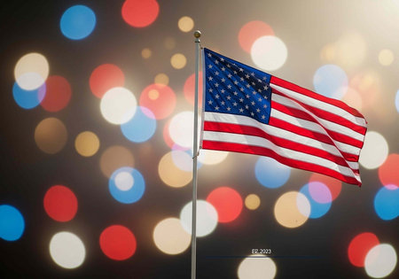A US flag on a pole with colorful bokeh lights shining behind it at night